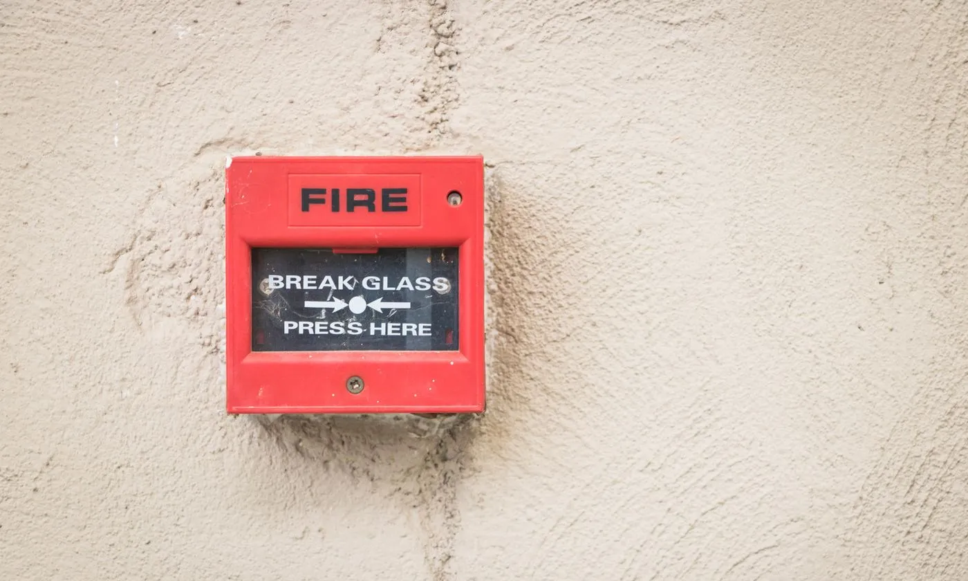 Red manual fire alarm call point mounted on a wall