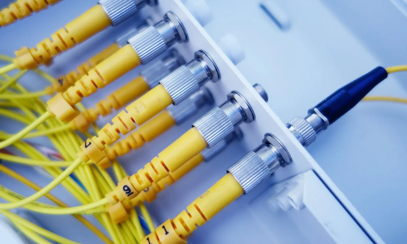 Yellow single-mode fiber-optic patch cords with metal FC connectors at an optical patch panel